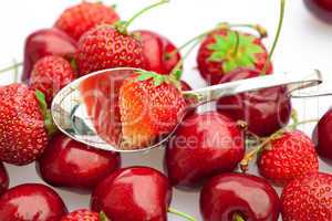 cherry and strawberry in a spoon isolated on white