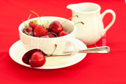 milk jug, cup, saucer and spoon  on a red background