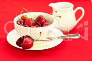 milk jug, cup, saucer and spoon  on a red background