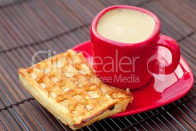 cup of cappuccino wafers and coffee beans on a bamboo mat