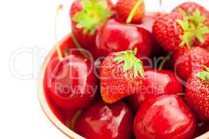 strawberries and cherries in a bowl isolated on white