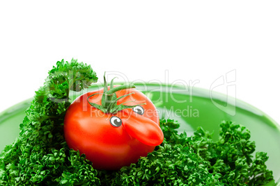 tomato with eyes lying on a plate with greens