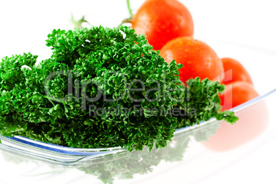 tomatoes and greens with water drops in a glass