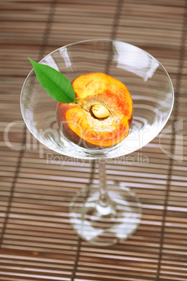 peach with a leaf and a martini glass on a bamboo mat