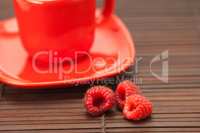 Raspberry, cup with a plate on a bamboo mat