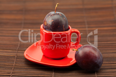 plum  in a cup and saucer on a bamboo mat