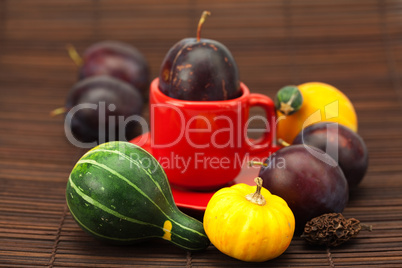 Plum, cup, China pumpkin on a bamboo mat