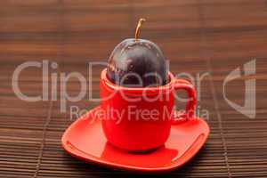 plum  in a cup and saucer on a bamboo mat
