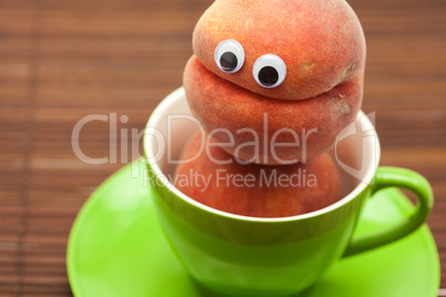 Peach with eyes in the cup and saucer on a bamboo mat