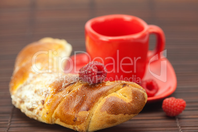 Cup with a plate , raspberry and roll on a bamboo mat