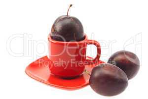 plum in a cup and saucer isolated on white