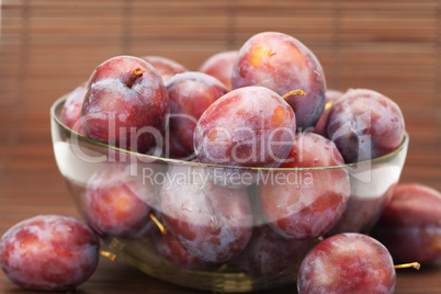 plums in a glass bowl on a bamboo mat