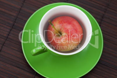 cup, saucer and apples on a bamboo mat