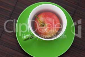 cup, saucer and apples on a bamboo mat