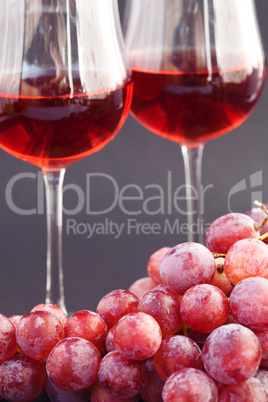 glass of wine and a bunch of grapes on a black background