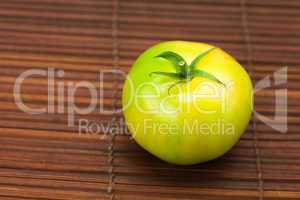 green tomato on a bamboo mat