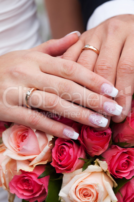 hands of the bride and groom with the rings lying on the bouquet