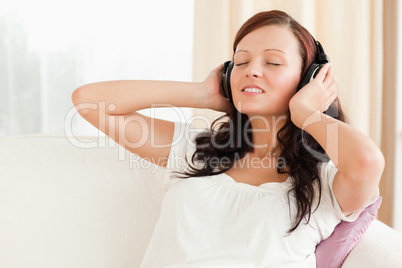 Dark-haired woman relaxing on a sofa with headphones