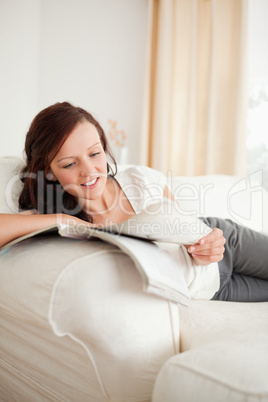 Young red-haired woman studying on the sofa