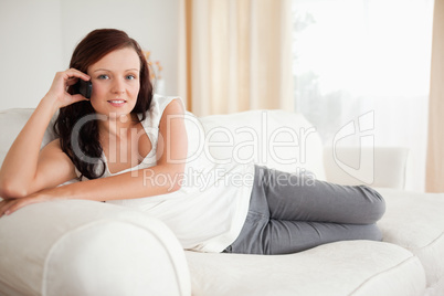 Smiling woman on the phone relaxing on a sofa