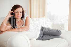 Smiling woman on the phone relaxing on a sofa