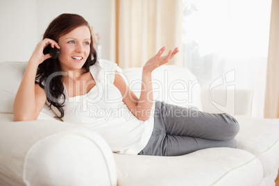 Red-haired woman relaxing on a sofa phoning