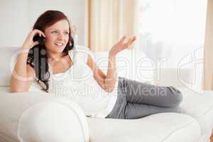 Red-haired woman relaxing on a sofa phoning