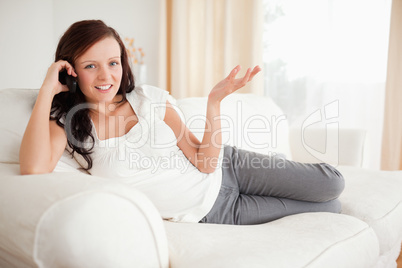 Red-haired woman relaxing on a sofa phoning looking into the cam