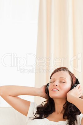 Red-haired woman relaxing on a sofa listening to music
