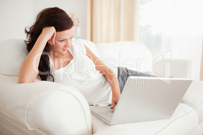Red-haired woman relaxing on a sofa surfing the internet