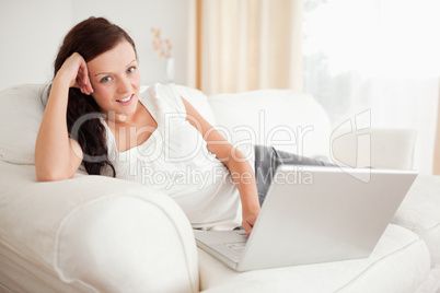 Red-haired woman relaxing on a sofa surfing the internet looking