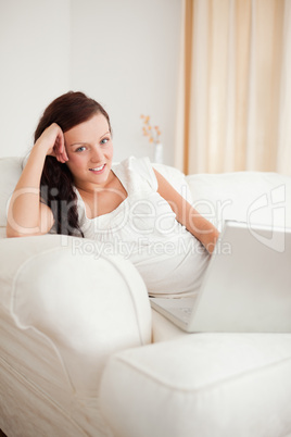Beautiful red-haired woman relaxing on a sofa surfing the intern