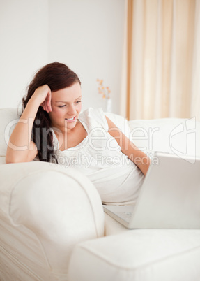 Beautiful red-haired woman relaxing on a sofa surfing the intern