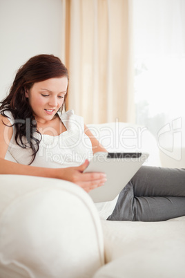 Beautiful red-haired woman relaxing on a sofa with a tablet