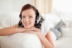 Relaxed red-haired woman with headphones looking into the camera