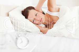Gorgeous red-haired woman lying in bed not wanting to hear the a