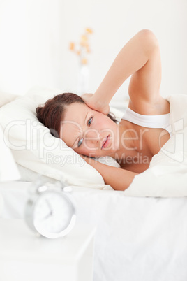 Cute red-haired woman lying in bed not wanting to hear the alarm