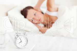 Good looking red-haired woman lying in bed not wanting to hear t