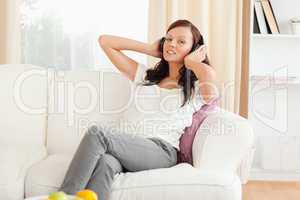 Gorgeous red-haired woman relaxing on a sofa listening to music