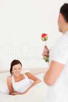 Young woman looking into camera when husband arrives with rose
