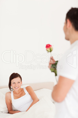 Handsome guy with a rose looking into the camera