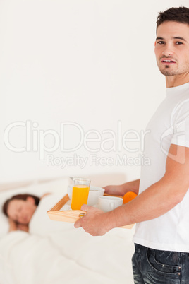 Man bringing breakfast to his sleeping wife