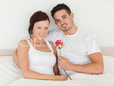 Happy couple in a bed with a rose
