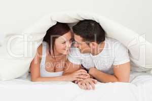 Happy couple hiding under a blanket