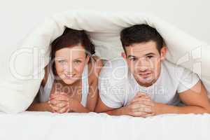 Happy couple hiding under their bvlanket