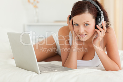 Woman listening to music working on a laptop looking at the came