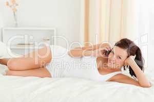 Charming Woman phoning on her bed looking into the camera