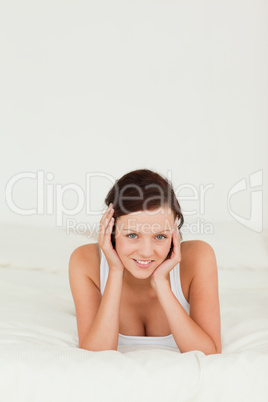 Red-haired woman lying on her bed looking into camera