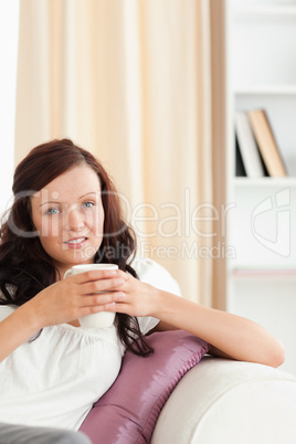 Close up of a woman holding a cup looking at the camera