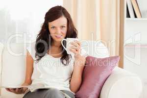 Relaxed woman sitting on a sofa with coffee and magazine